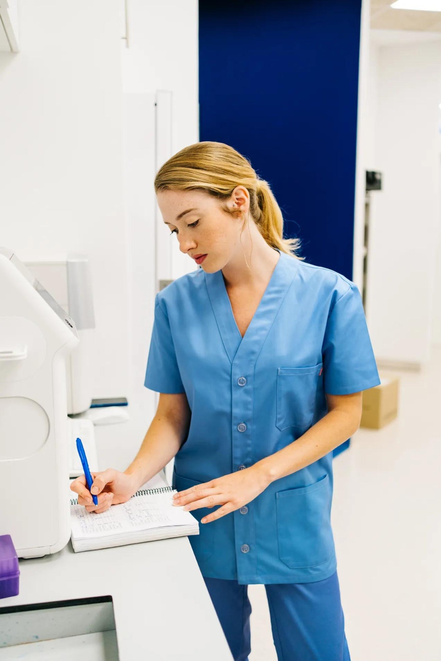 Personnel de santé en bleu, utilisant un clipboard avec une blouse médicale confortable