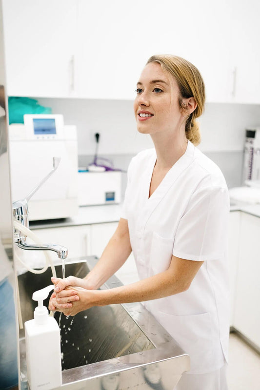 Femme en blouse médicale Daisy avec coupe confortable lavant ses mains au lavabo