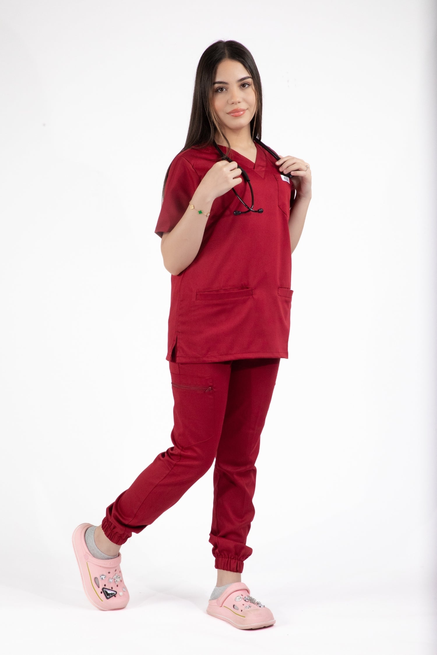 Femme portant l’uniforme médical Slimfit NEW: une blouse et un pantalon rouge bordeaux